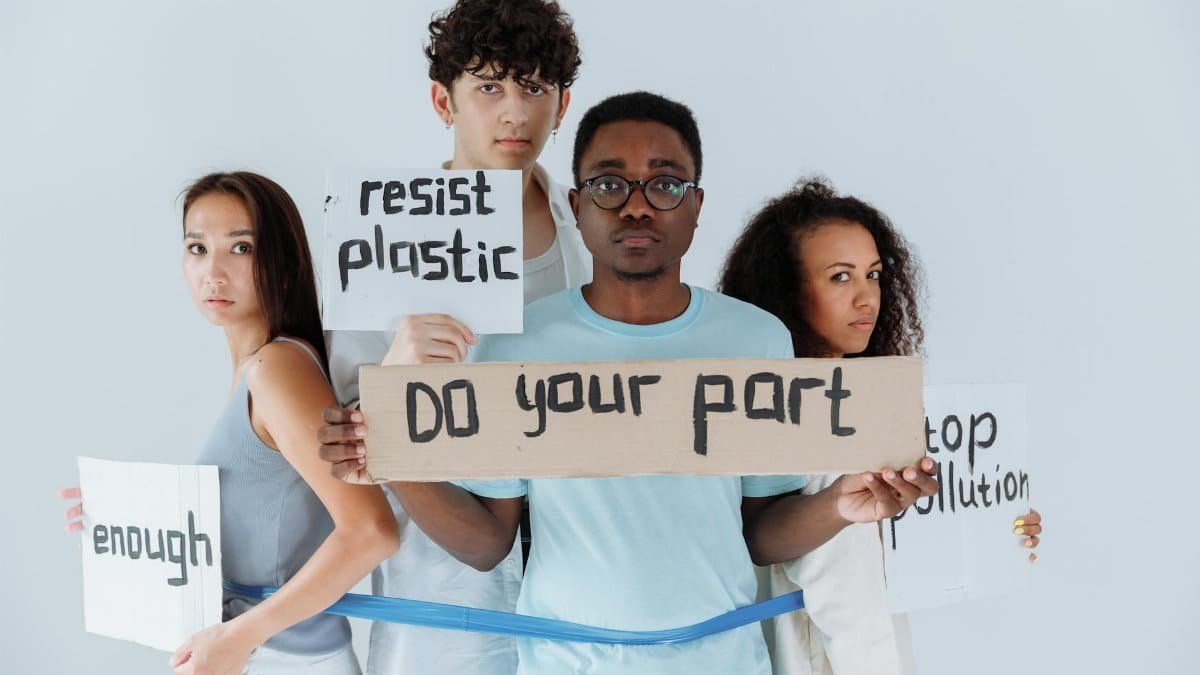 A diverse group of young adults holding signs promoting anti-plastic and pollution awareness.