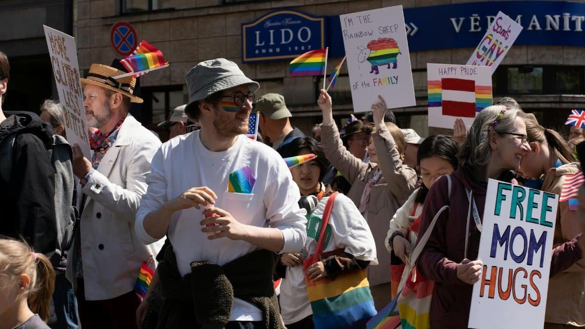 Celebration at a vibrant LGBTQ+ pride parade in Riga. People with signs and flags promoting acceptance.