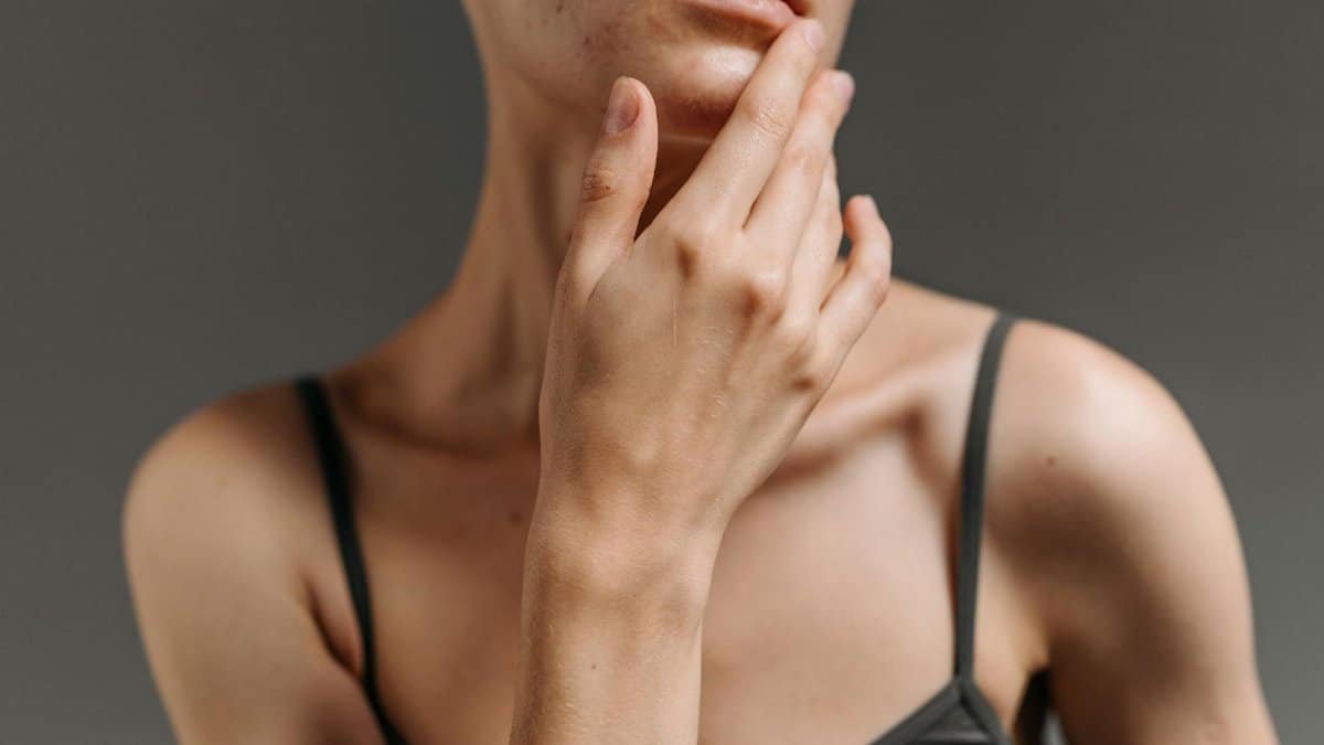 Artistic close-up photo highlighting a woman's hand touching her face, set against a gray background.