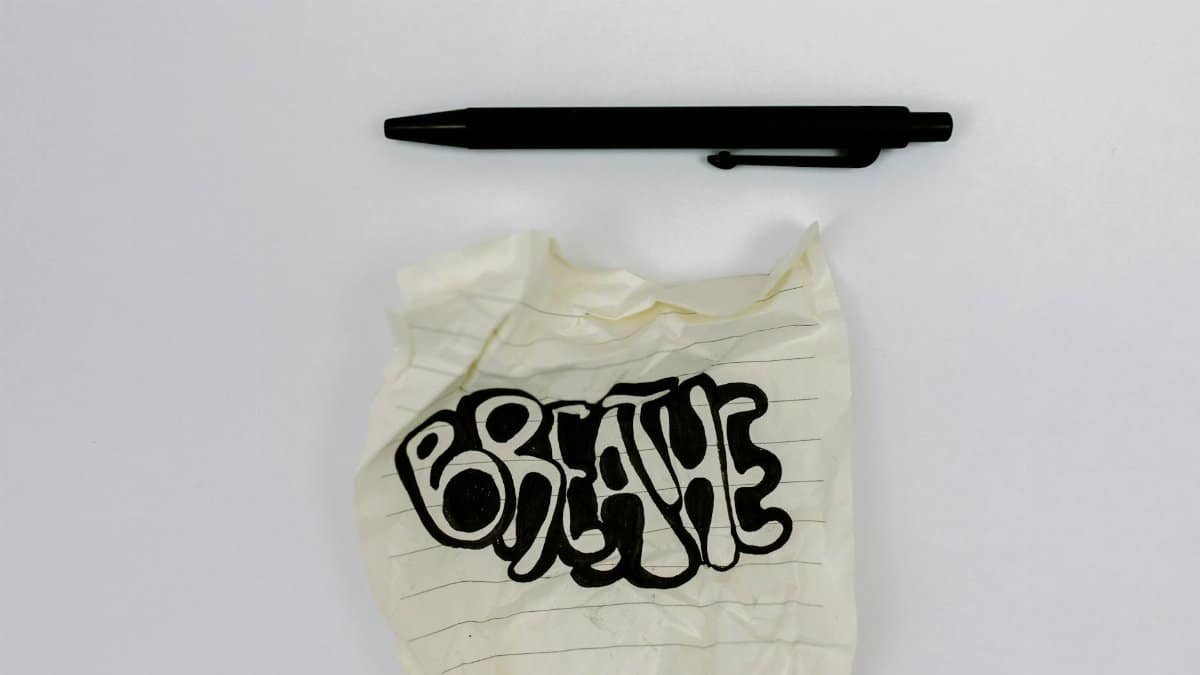 A crumpled note with the word 'Breathe' beside a black pen on a white background.