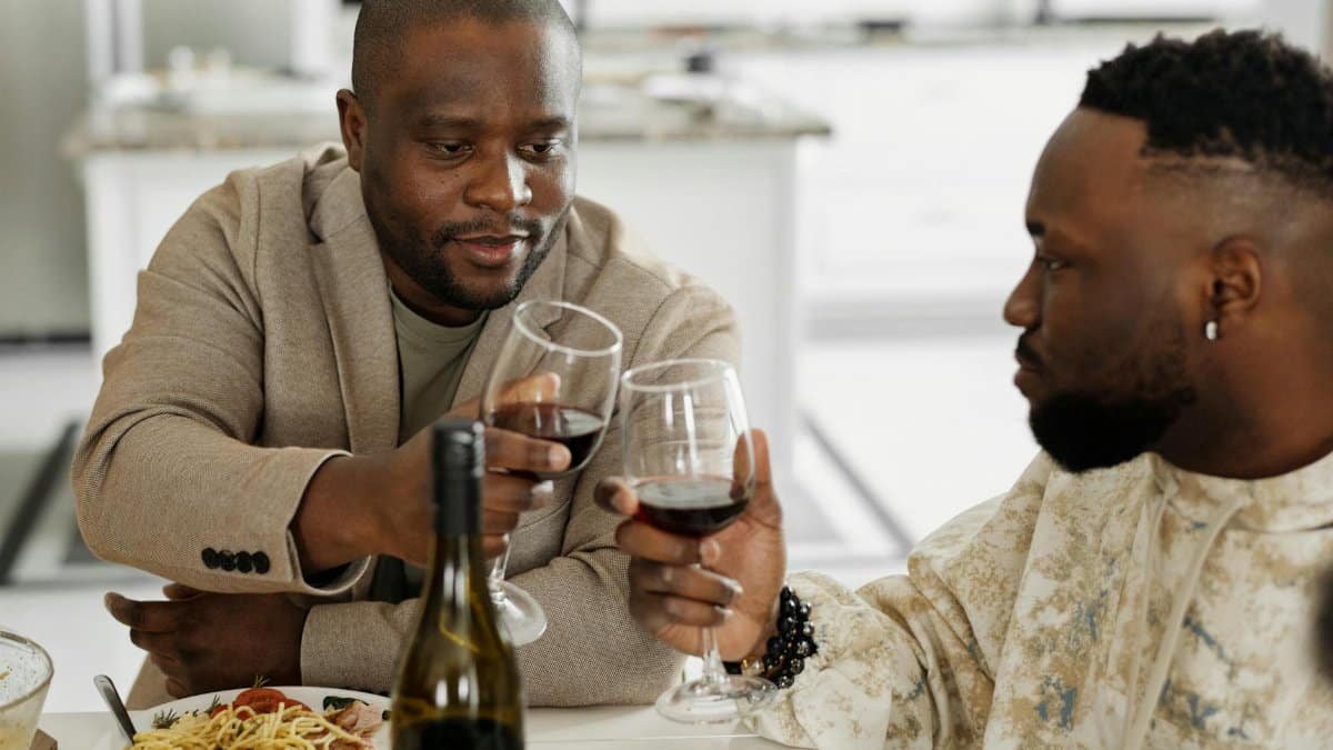 Two men sharing a toast with red wine during a cozy dinner at home.