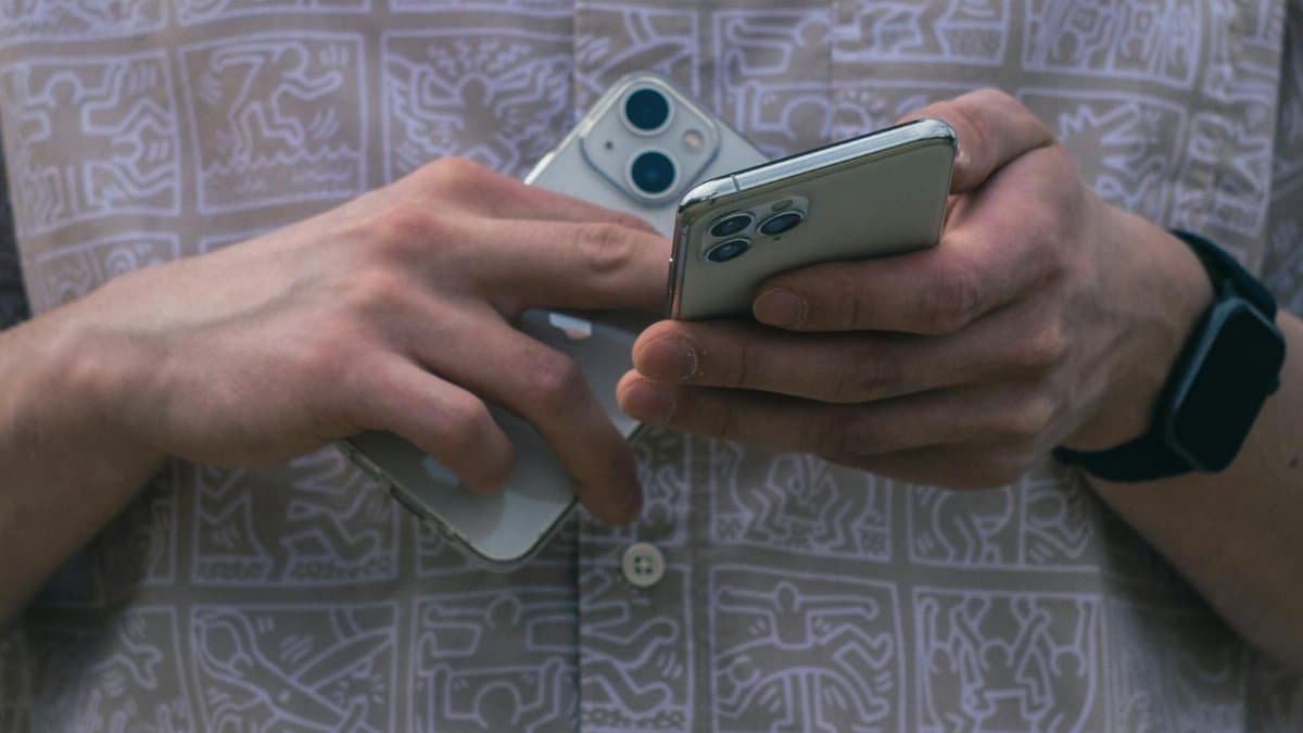 Detail of hands holding two smartphones, showcasing modern technology usage.