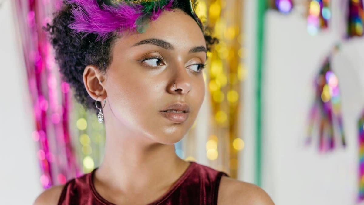 A portrait of a young woman in a masquerade mask at a colorful Mardi Gras celebration.