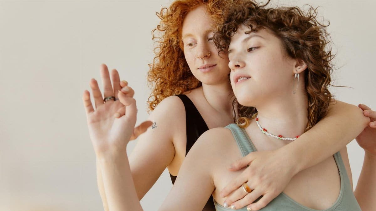 Intimate studio shot of two women with curly hair embracing, showcasing love and connection.