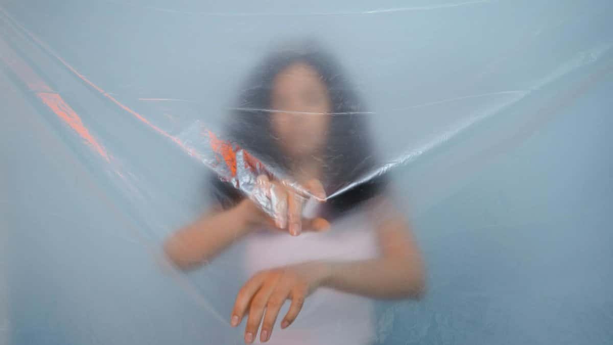 Blurred person behind translucent plastic, evoking mystery and abstraction.