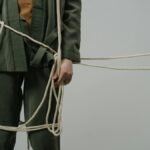 A captivating conceptual photograph showing a person in green clothes tangled with ropes, symbolizing entrapment or struggle.