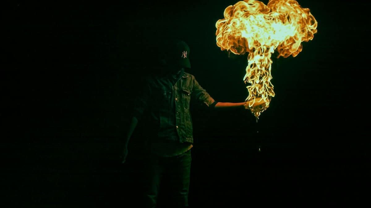 An adult holding a controlled flame explosion in a nighttime display.