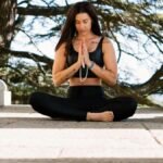 Woman practicing meditation in nature amidst stone columns, promoting peace and mindfulness.