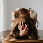 A woman showing despair with her head down on a table, indicating stress.