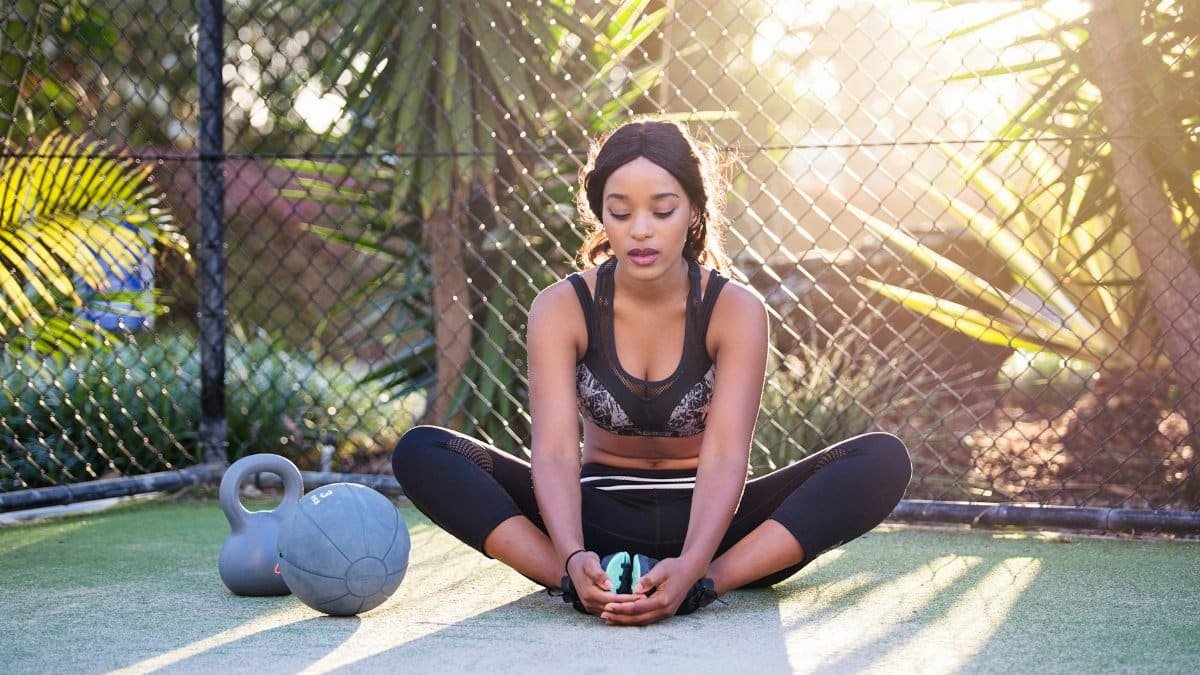 Woman practicing outdoor yoga and fitness on a sunny day with kettlebell, showcasing an active lifestyle.