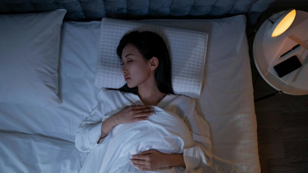 Calm and peaceful woman resting in bed under dim lighting, promoting relaxation.