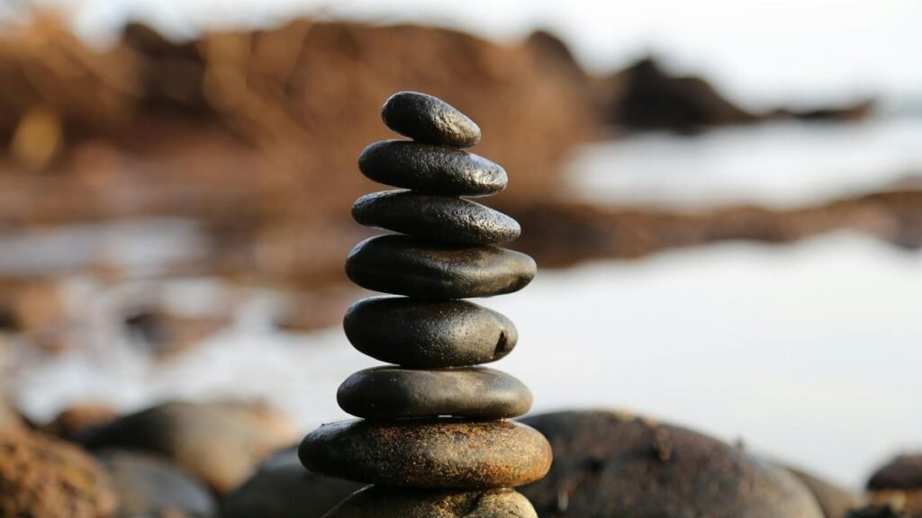 A stack of smooth stones artfully balanced by a waterside, evoking tranquility and zen.