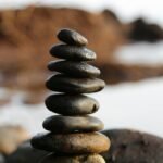 A stack of smooth stones artfully balanced by a waterside, evoking tranquility and zen.