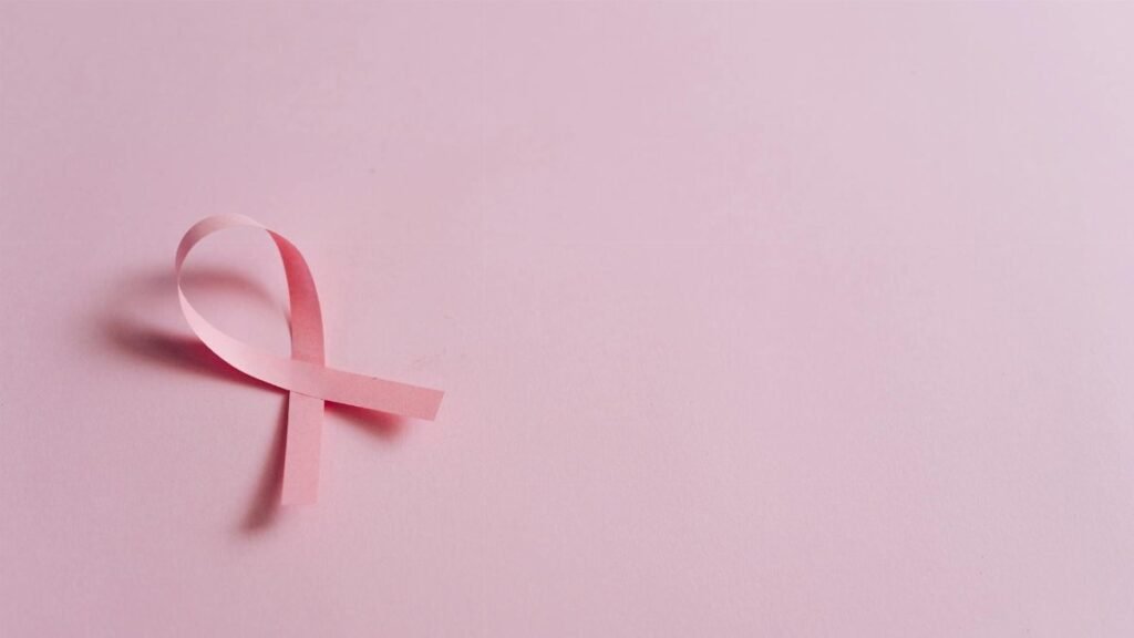 Minimalist pink ribbon symbolizing breast cancer awareness on a pink background.