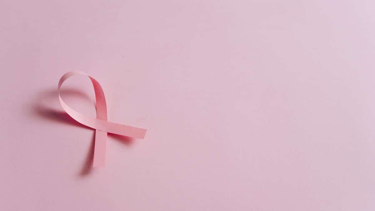 Minimalist pink ribbon symbolizing breast cancer awareness on a pink background.