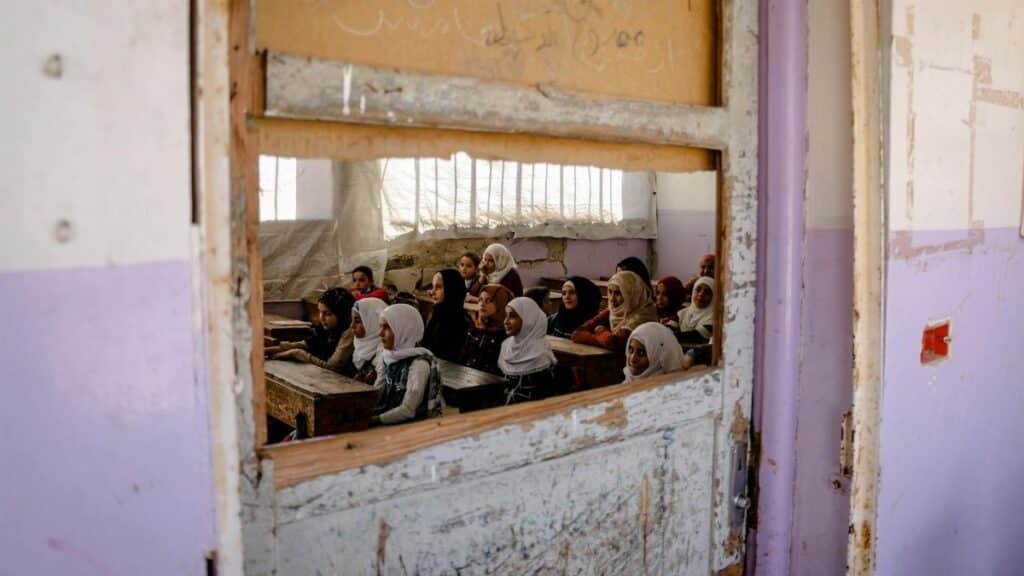 A group of girls attending class in a rundown school in Idlib, Syria, showcasing resilience amid challenging conditions.