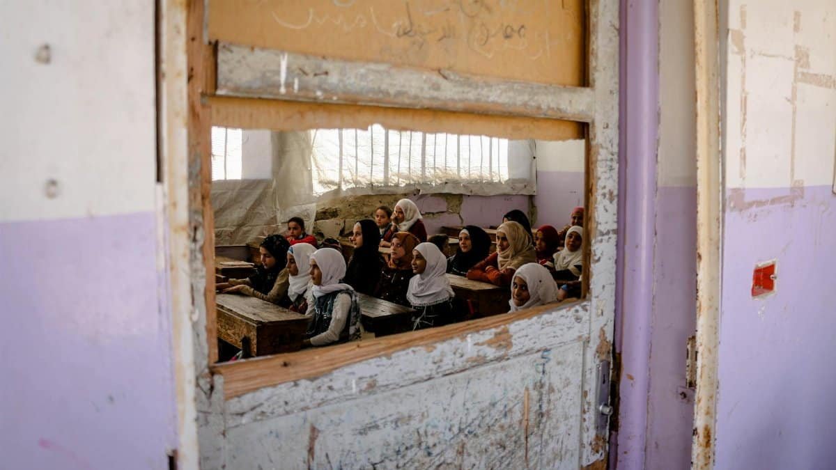 A group of girls attending class in a rundown school in Idlib, Syria, showcasing resilience amid challenging conditions.