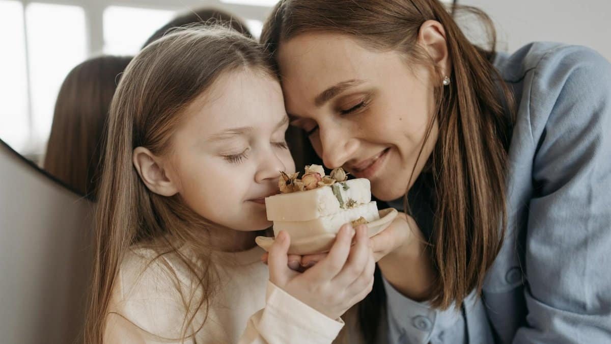 A close-up of a mother and daughter bonding over a beautifully crafted aromatic soap.