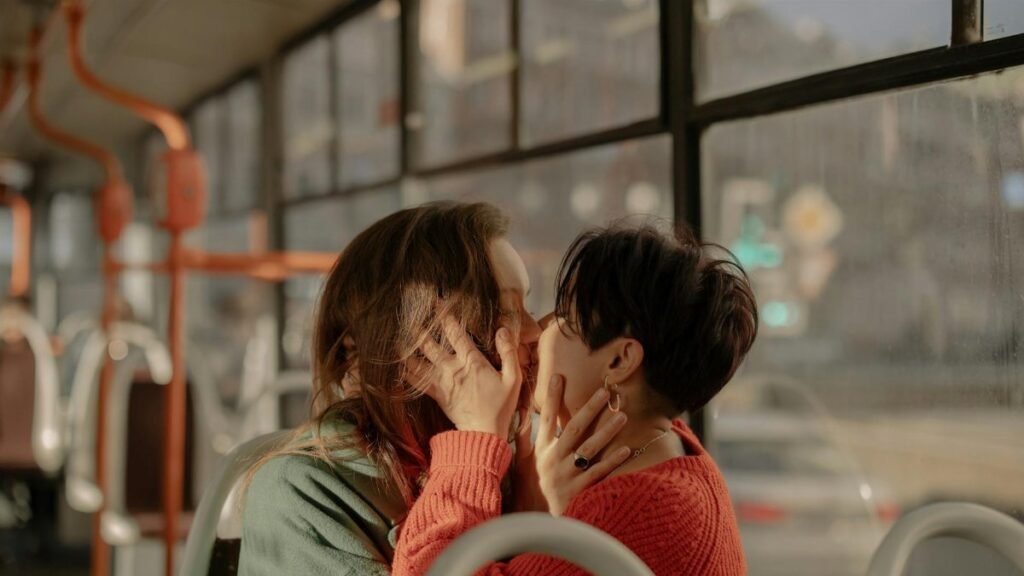 A loving moment between two women on a bus displaying affection and intimacy.