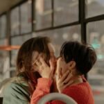 A loving moment between two women on a bus displaying affection and intimacy.