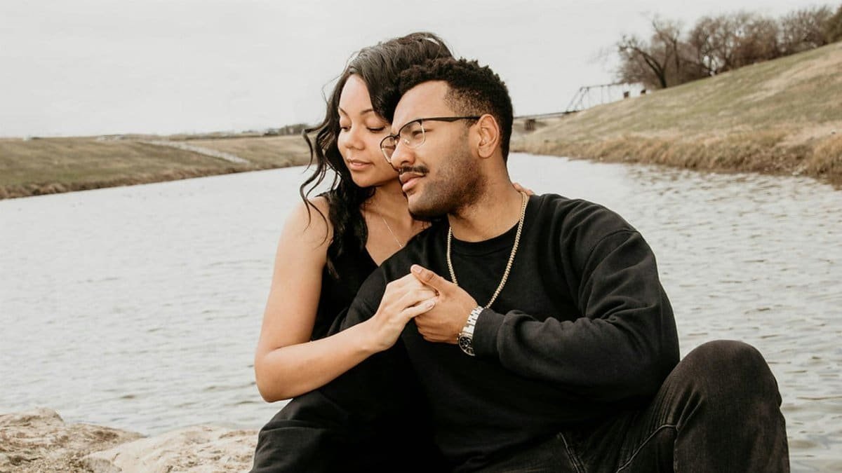 Couple enjoying a tender moment outdoors by a serene lake, showcasing love and togetherness.