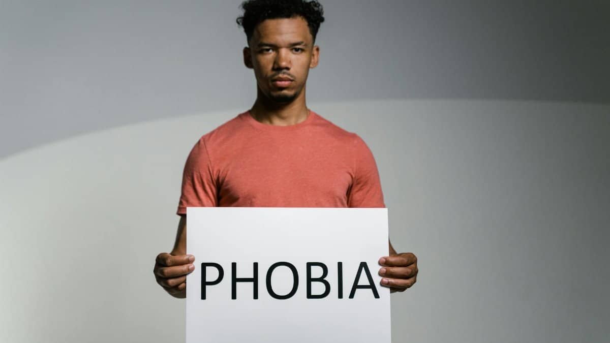 A man holding a sign that reads 'PHOBIA' symbolizes awareness and feelings of fear and anxiety.