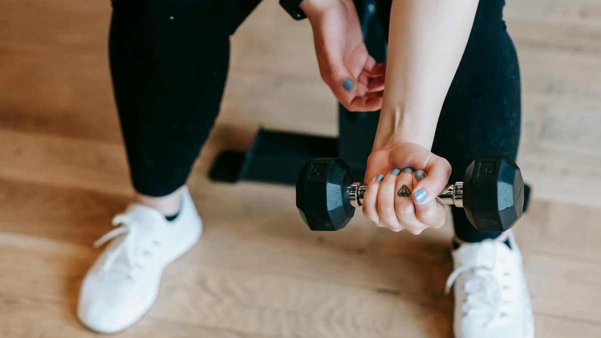 A woman working out with a dumbbell, emphasizing strength and fitness indoors.