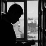 A moody silhouette of a man reading in a library, capturing solitude and contemplation.