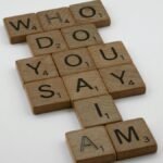 Wooden scrabble tiles arranged to spell 'Who do you say I am' on a white background.