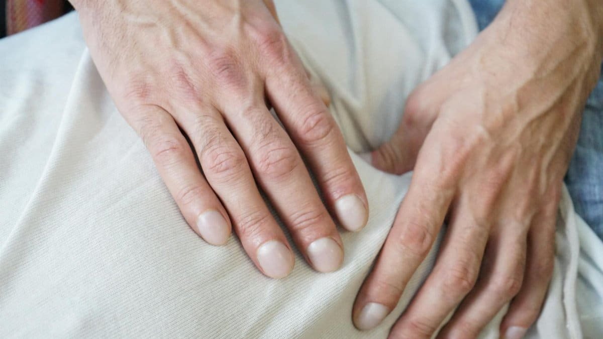 Detailed view of hands giving a soothing massage on a white fabric indoors. Perfect for wellness themes.