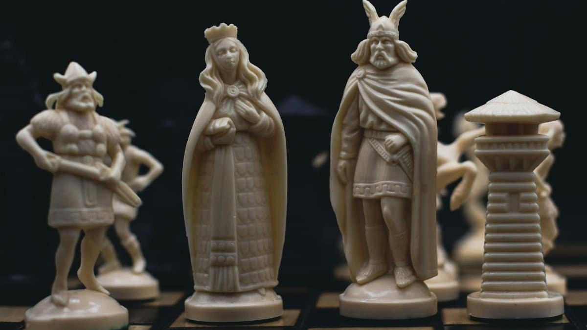 Detailed close-up of intricately carved chess pieces on a chessboard, evoking a medieval theme.
