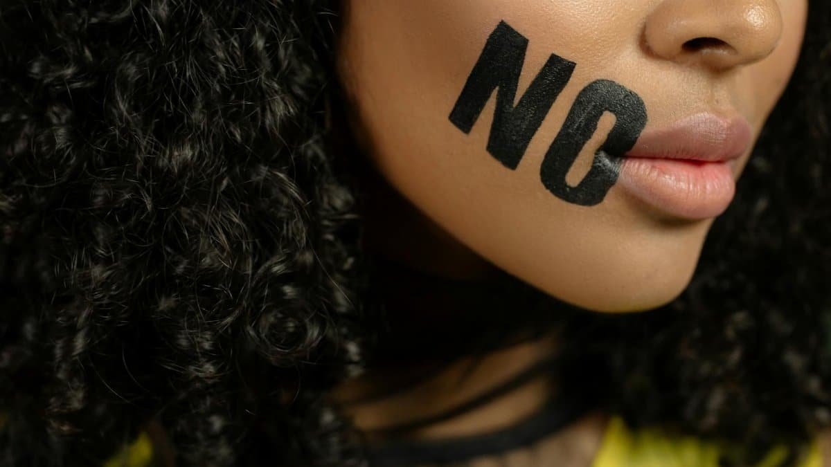 Close-up of a woman with 'No' painted on her face, conveying a powerful message.