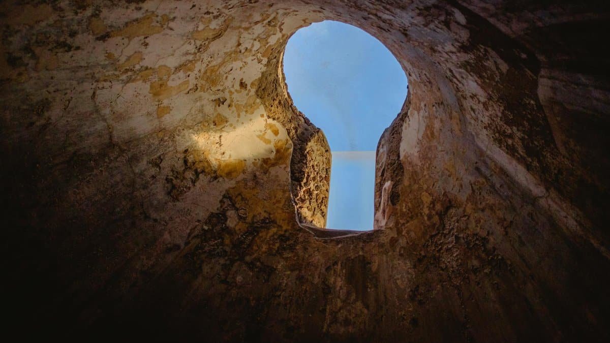 A captivating view of the blue sky through a keyhole-shaped opening in an ancient wall in Pompei.