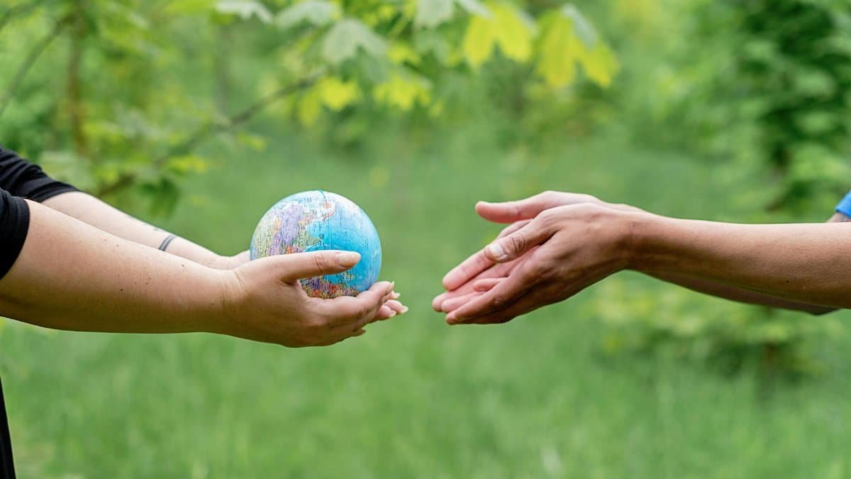 Two hands exchanging a small globe symbolizing global unity and ecology awareness.
