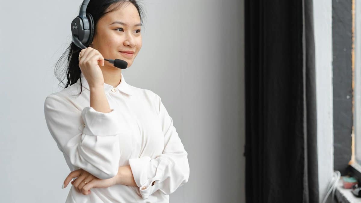 Professional Asian woman with headset providing customer support in an office setting.