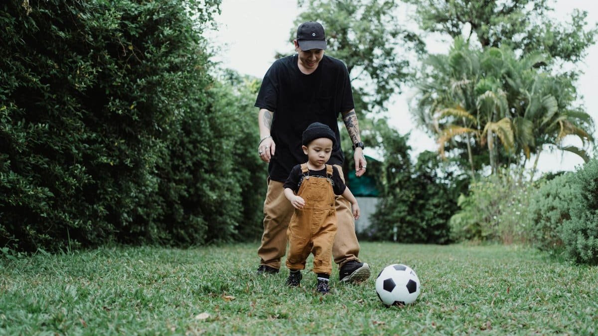 A father and son enjoying a playful game of soccer together in the backyard.