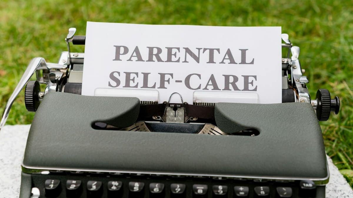 A vintage typewriter showcasing a "Parental Self-Care" message on paper outdoors.