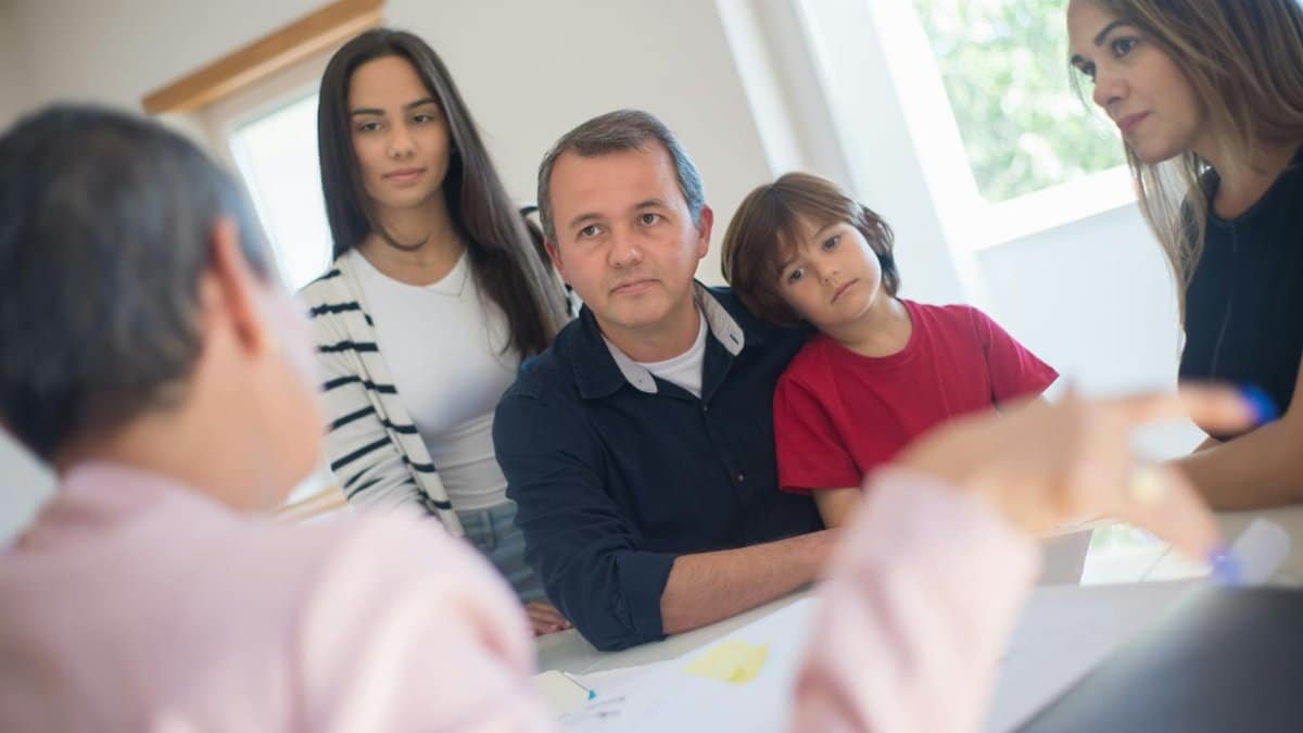 A family of four seeks advice from a professional during an indoor consultation in a bright room.