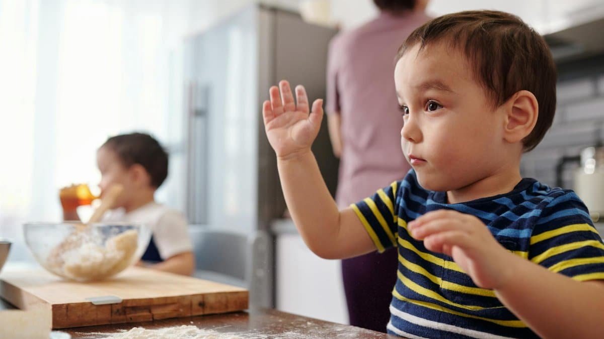 Two young children baking in a home kitchen, learning and having fun.
