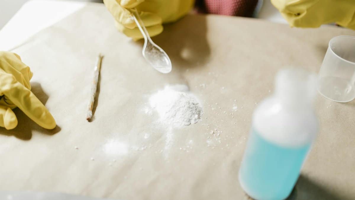 Close-up of a science experiment with yellow gloves, powder, and blue liquid indoors.