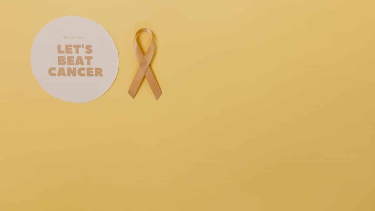 Minimalist design featuring a gold cancer awareness ribbon on yellow background.