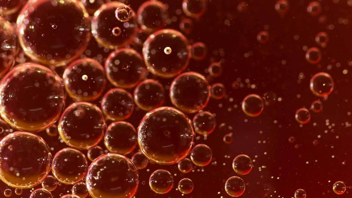 Macro image of oil bubbles in liquid on a vibrant red background.