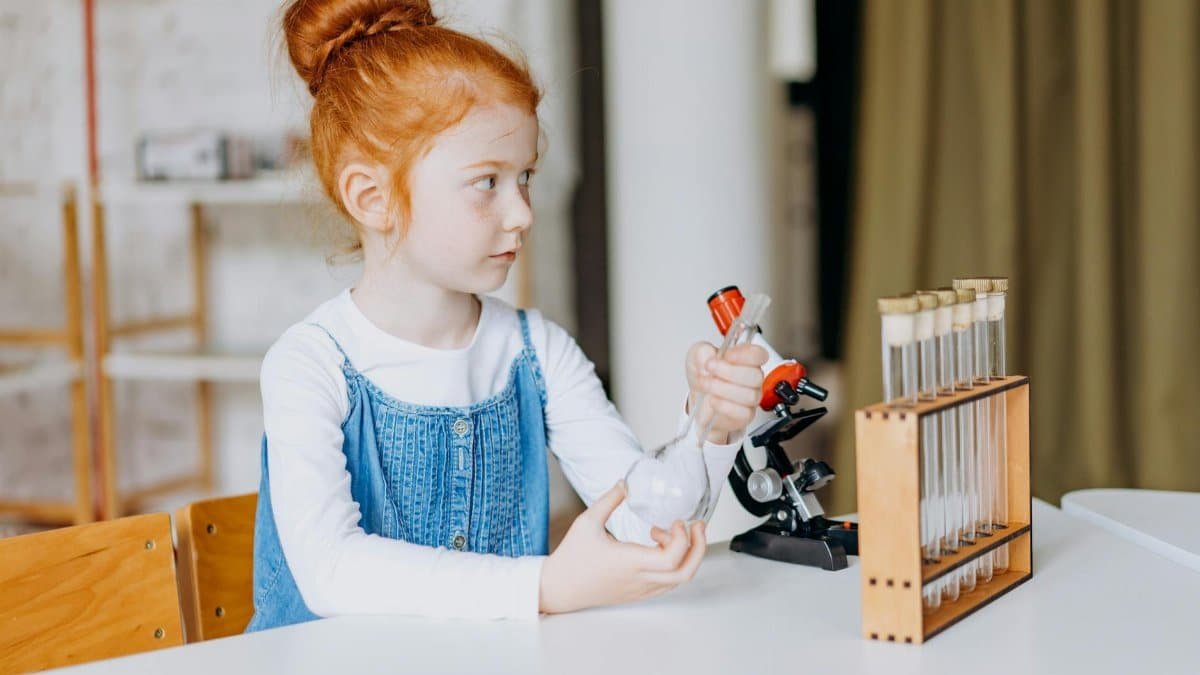 A young girl explores science with test tubes and microscopes in a bright indoor setting.