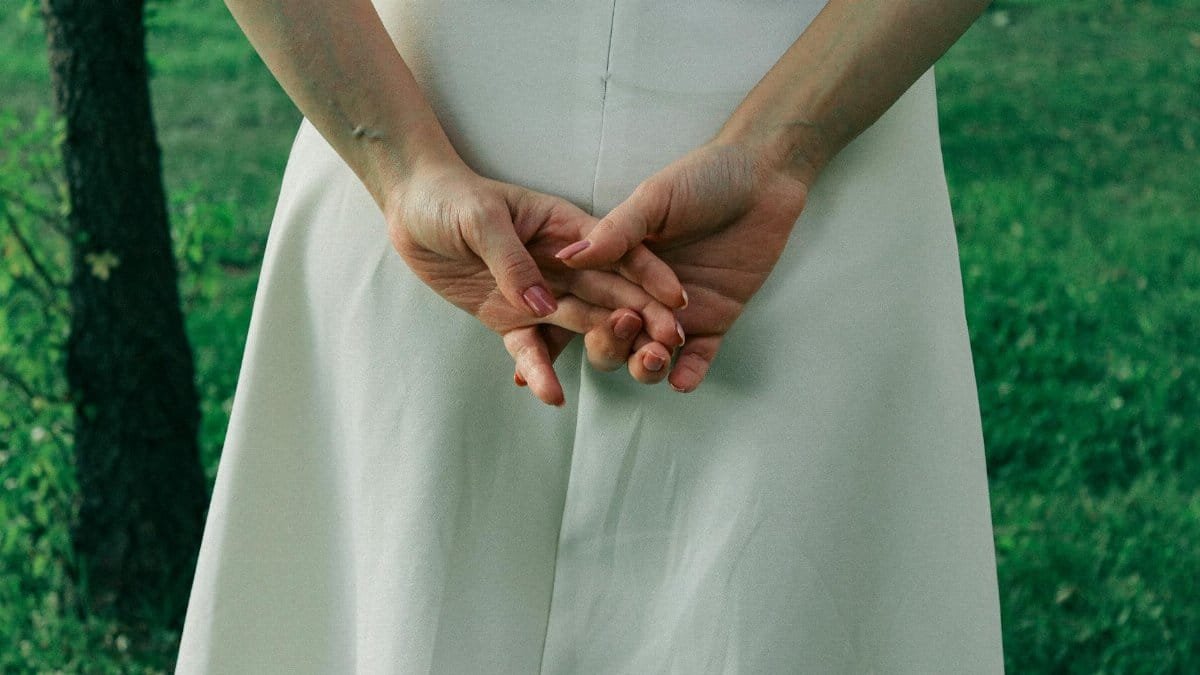 A serene close-up of hands clasped behind back outside on grass.