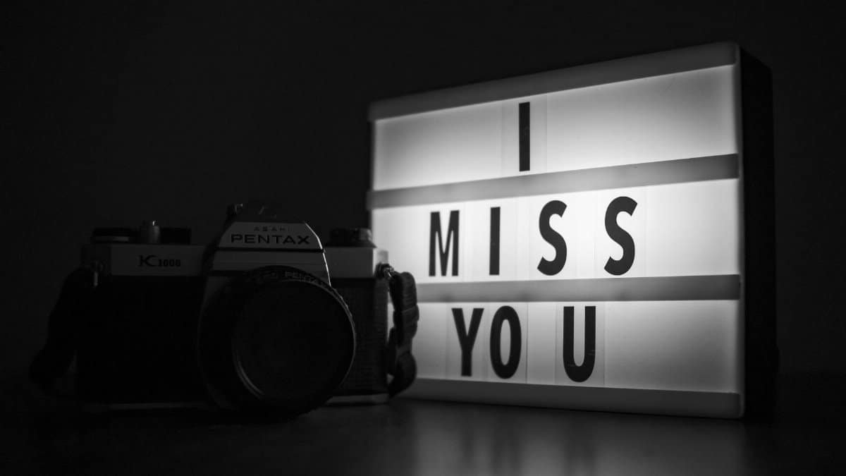 A vintage Pentax camera beside a lightbox reading 'I miss you' in black and white.