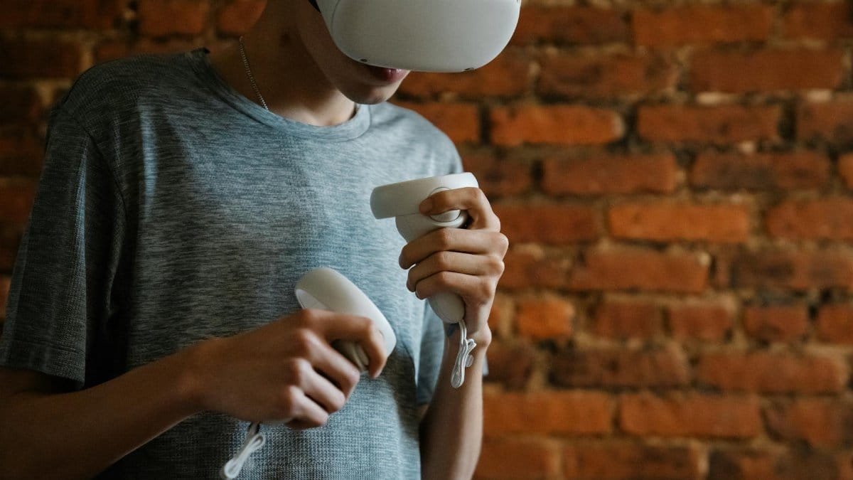 A young man engaging with virtual reality using a VR headset and controllers indoors.