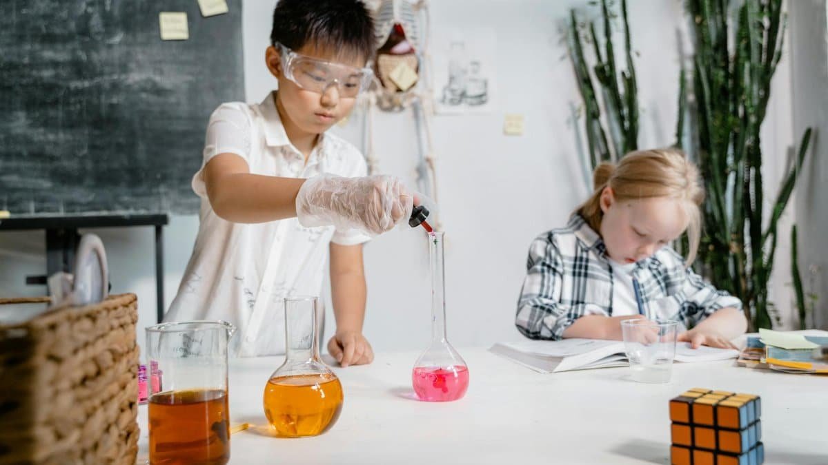Two children engaged in a science experiment with lab equipment in a classroom.