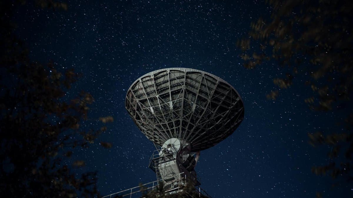 A large radio telescope beneath a starry night sky capturing celestial signals.