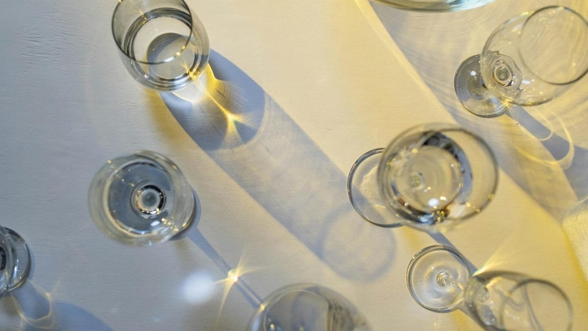 Crystal glasses on a table casting intricate shadows in sunlight, creating an artistic effect.