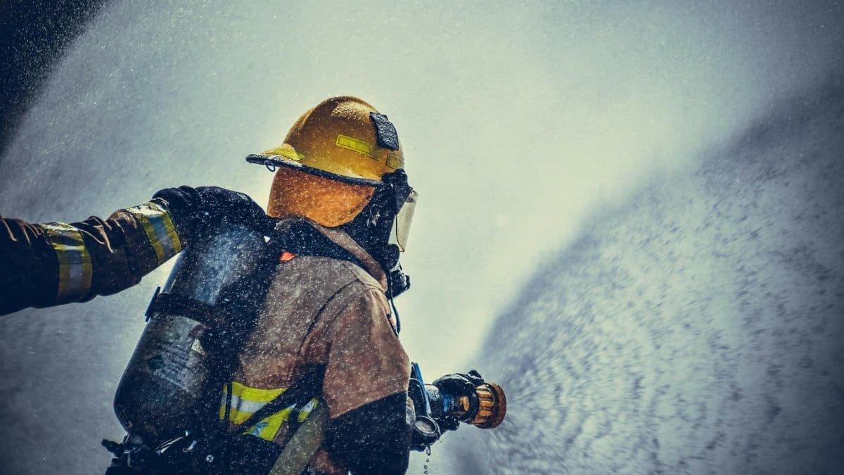 A brave firefighter in protective gear sprays water during training or emergency.